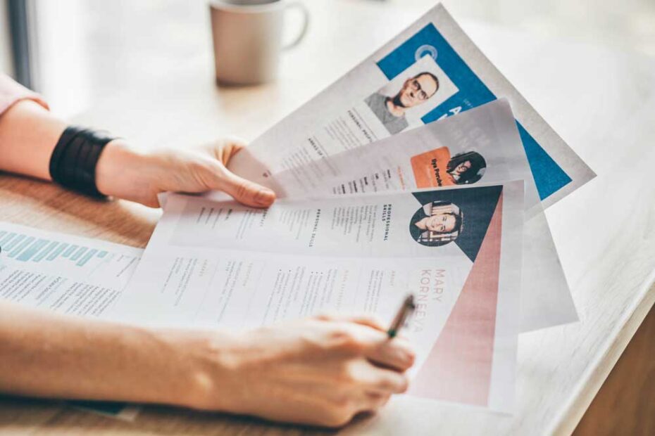 A manager looking at a pile of CVs that have photographs on